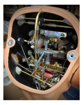 Interior of a ventriloquial figure's head showing the rods, levers, springs and mechanical linkages built by Chance Wolf